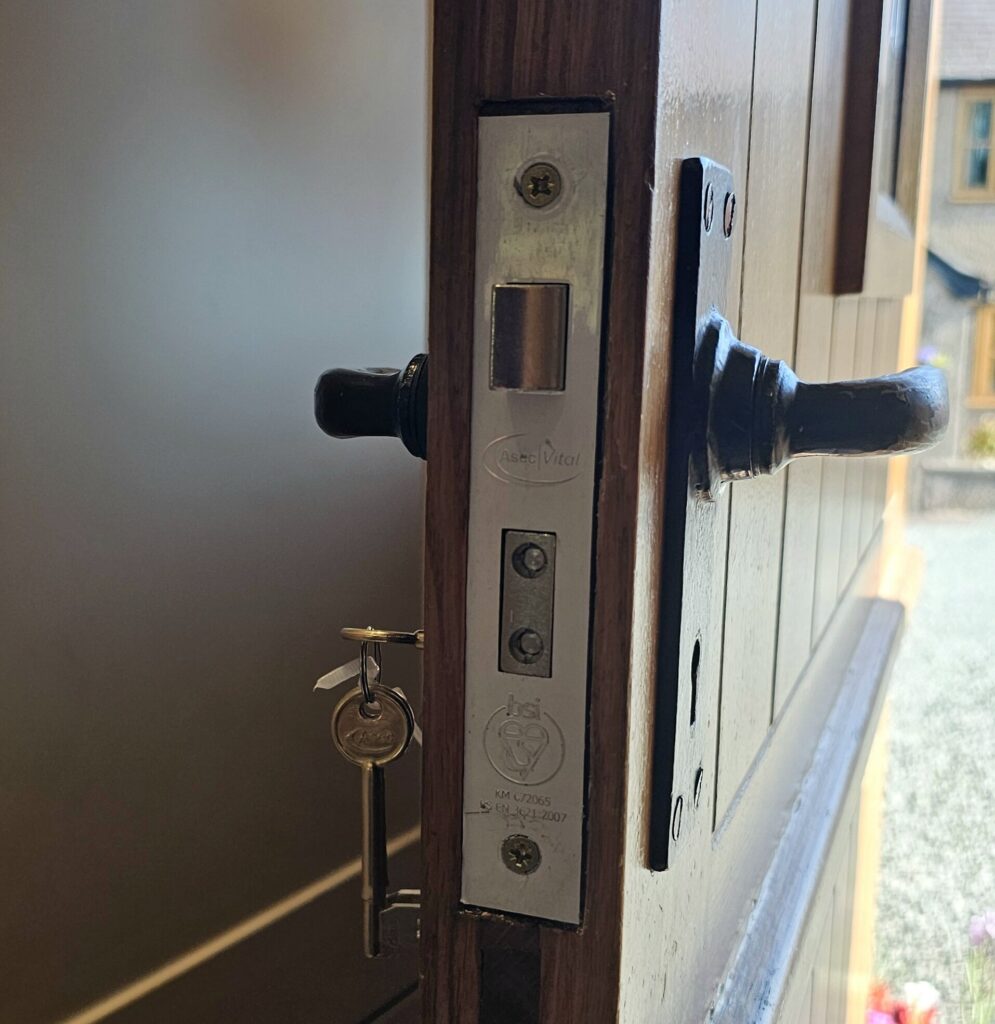 Locksmith changing a mortice lock on a wooden door in Wrexham for Wrexham Council